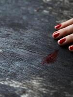 Hand with red nail polish grazed on worn wooden surface creating a mysterious scene photo
