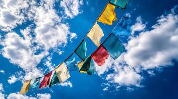 Colorful Tibetan Prayer Flags Swaying in the Wind Against a Bright Blue Sky and Fluffy White Clouds photo