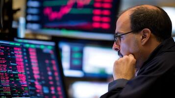 Focused Trader Analyzing Stock Market Trends and Data on Multiple Screens photo