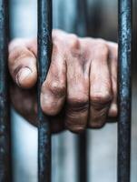 Rugged Hands Clutching Rusty Prison Bars with Aged Skin and Weathered Texture in Focus photo