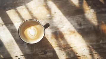 Single cup of coffee casting shadows on rustic wooden table in a warm sunlit setting photo