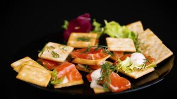 small snack canapes with crackers and lightly salted red fish Salmon, isolated on black background video