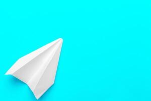 Flat lay of white paper plane and blank paper on pastel blue color background photo