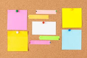 Cork board with several colorful blank notes with pins photo