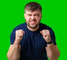A strong man with fists raised, smiling confidently, on a bright green background photo