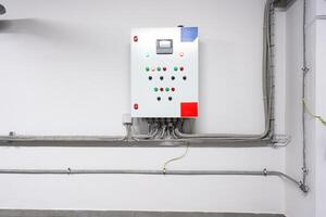 Control panel mounted on a wall with various indicator lights and buttons in an industrial setting photo