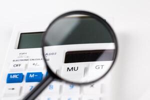 Calculator with a magnifying glass on a white background photo