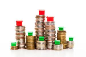 Stacks of coins, green and red home. Mortgage concept by money house from coins photo