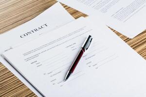 Pen and contract papers on wooden desk photo