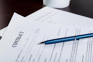 Pen and contract papers on wooden desk photo