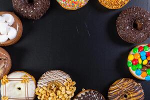 Assorted donuts from above on black background photo