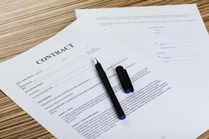 Pen and contract papers on wooden desk photo