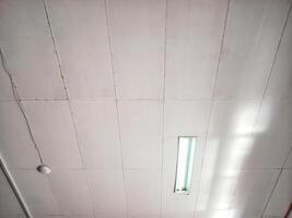 white rectangular tile suspended ceiling in office with a light and speakers photo
