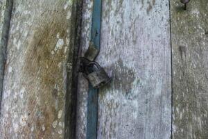 a door that is locked using a old padlock made of iron, building security photo