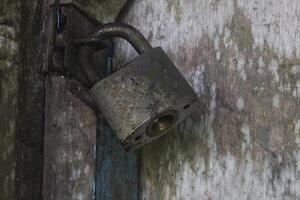 a door that is locked using a old padlock made of iron photo