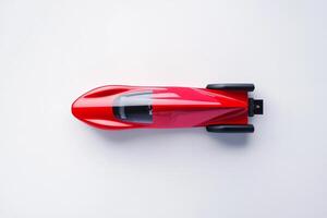 Red racing car model displayed on a white surface, showcasing sleek design and intricate details highlighted by natural lighting photo