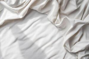 Soft white fabric draped elegantly on a surface, creating gentle folds and shadows in natural light photo