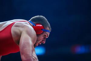 Wrestler prepares for competition wearing headgear at a sports arena during an intense match at night photo