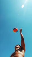 A person reaches for a colorful beach ball under a bright blue sky during a sunny day at the beach photo