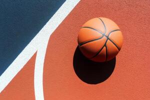 A basketball resting on a colorful court with vibrant lines under bright sunlight in an urban setting photo