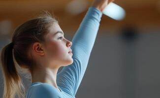 A young gymnast practicing her routine with determination in a training facility during an afternoon session photo