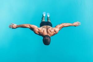 A man dives into clear blue water with arms extended, showcasing athleticism and grace during a warm summer day photo