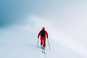 A skier navigates through fog-covered snowy terrain during winter in a remote mountainous region photo