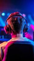 A gamer is focused on an online session, wearing headphones and surrounded by colorful lights in a contemporary gaming environment, creating an engaging atmosphere. photo
