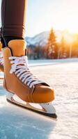Person skating on a sunlit frozen lake with scenic mountains in the background during winter afternoon photo