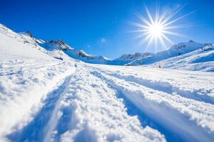 Snowy mountain landscape under a bright sun with fresh tracks in the white snow during winter photo