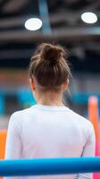 Young gymnast preparing for her routine at a training facility during a gymnastics practice session photo