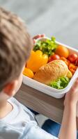 A young child enjoys a colorful lunch with vegetables and a sandwich at a bright kitchen table photo