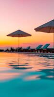 Serene sunset by the pool with umbrellas and lounge chairs at a tranquil resort in the evening sky photo