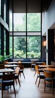 A serene dining area with large windows overlooking greenery in a modern restaurant during the day photo