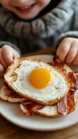 Young child enjoys homemade breakfast with fried egg and crispy bacon on toasted bread at the dining table photo