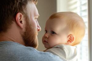A father holding his baby in a softly lit room while gazing out the window on a quiet afternoon photo
