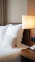 Cozy hotel room with soft white bedding, bedside lamp, and warm ambiance in a modern setting photo