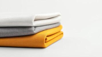 Three neatly folded fabric pieces in white, gray, and mustard yellow arranged on a clean, light background photo
