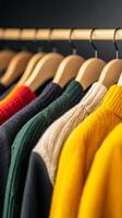 Colorful knitted sweaters arranged neatly on wooden hangers against a dark background in a cozy clothing store photo