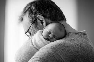 A father gently cradles his sleeping newborn in a cozy embrace during a calm morning at home photo