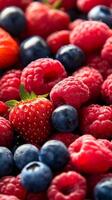 A vibrant assortment of fresh red raspberries, strawberries, and blueberries displayed together in a colorful arrangement photo