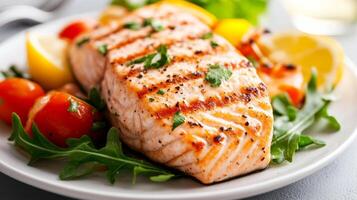 Grilled salmon served with fresh arugula, cherry tomatoes, and lemon wedges on a white plate for a vibrant meal experience photo