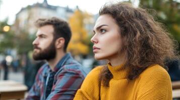 Couple sitting together in a park reflecting on life during a cool autumn afternoon while surrounded by colorful foliage photo