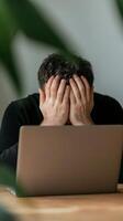A young man experiencing stress while working on a laptop in a cozy indoor setting during a calm day photo