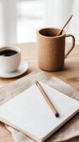 Cozy workspace with a notebook, pencil, and coffee cups on a wooden table in a soft morning light photo