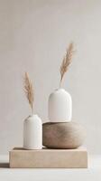 Minimalist decor featuring ceramic vases and pampas grass on a wooden platform in a soft beige setting photo