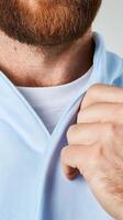 Man adjusting his collar in a light blue hoodie indoors photo