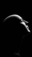 A serene profile of a mannequin with a smooth surface against a black background photo