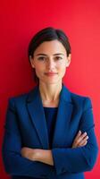 Confident businesswoman poses with arms crossed against a vibrant red background photo