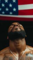 A man with a beard gazing upward under an American flag in a gym, reflecting determination and strength during a workout session photo